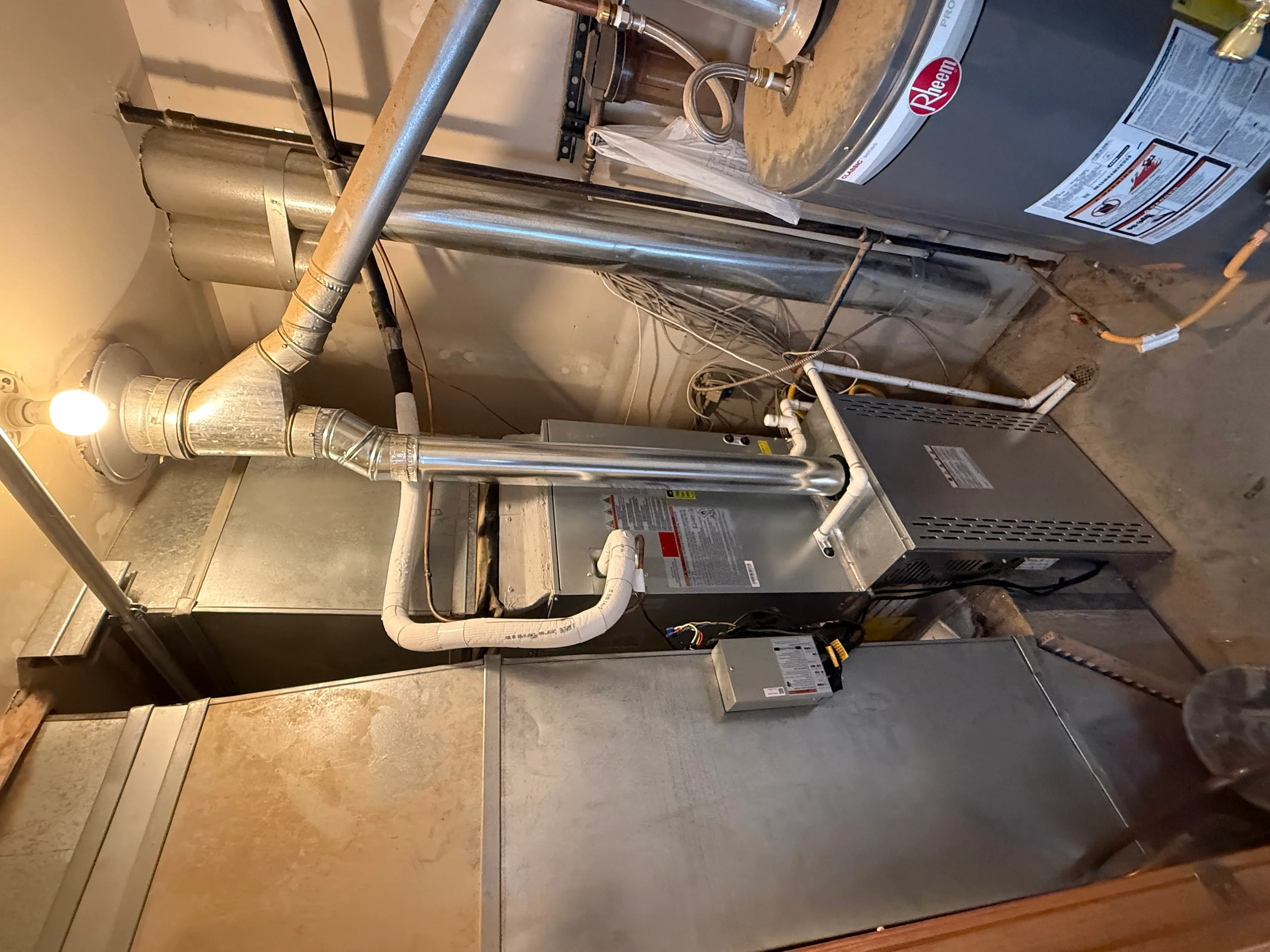 Installed water heater with copper piping, PVC connections, and electrical panel in utility space