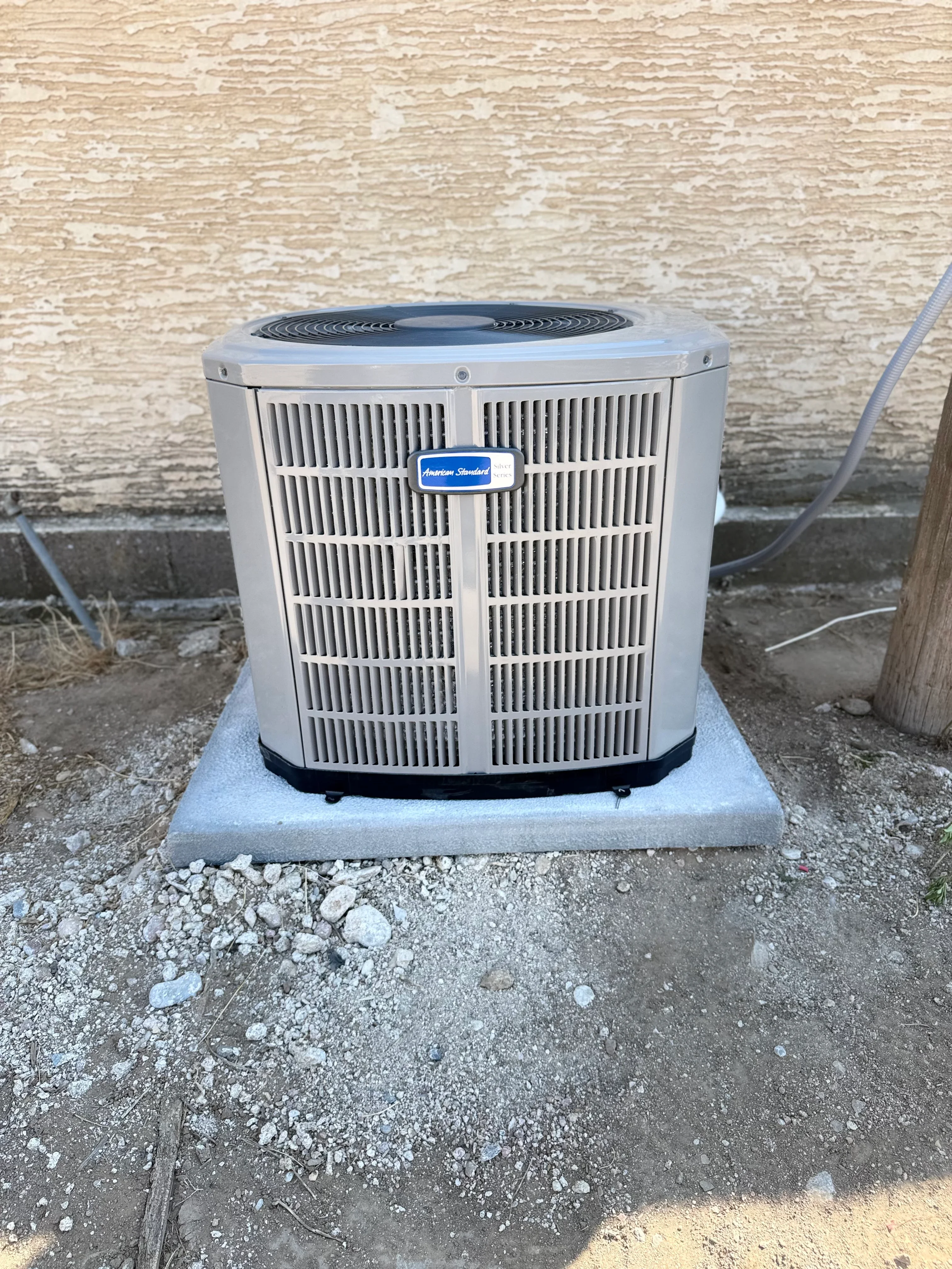 New American Standard AC condenser unit installed on concrete pad with refrigerant lines