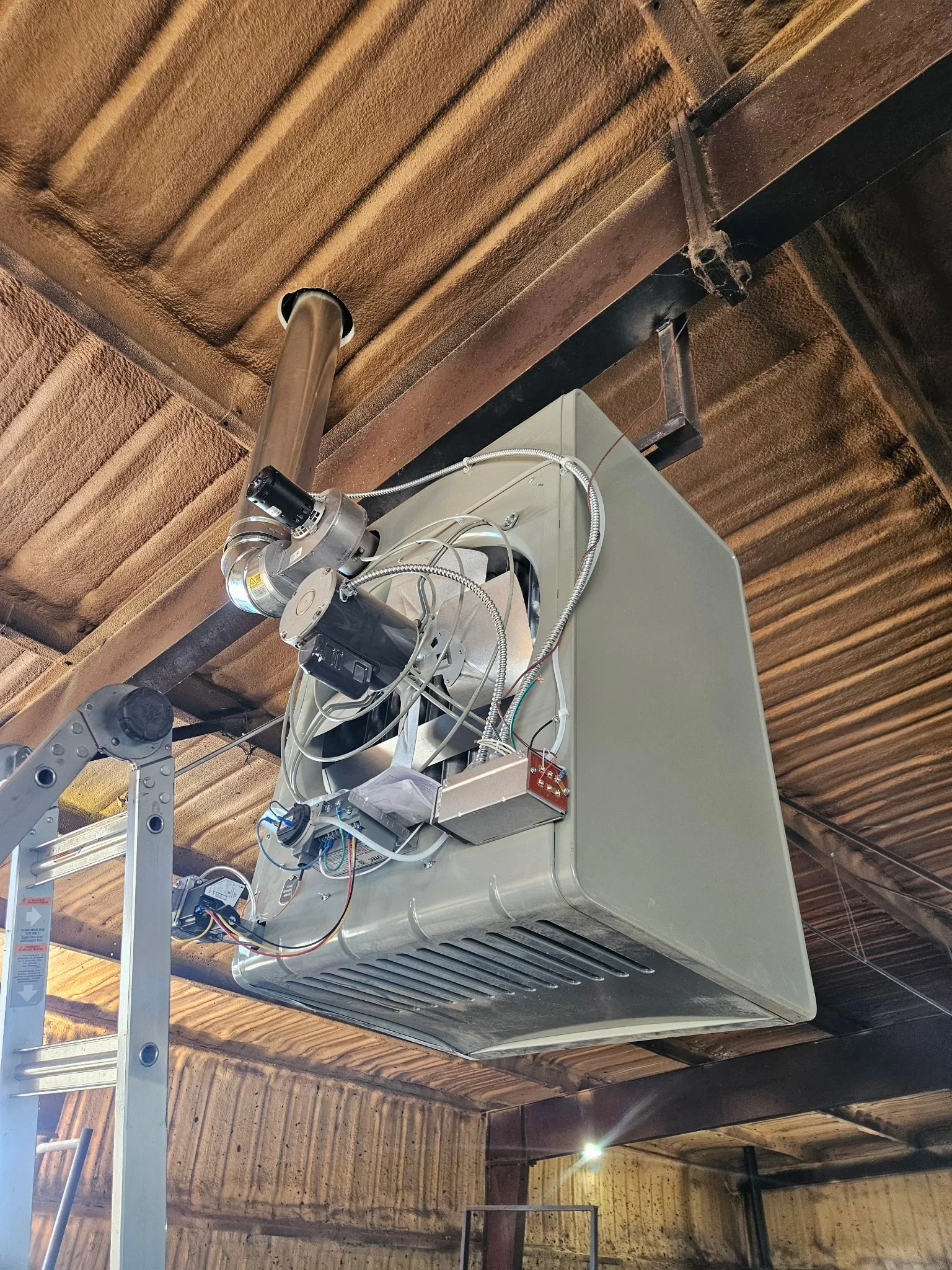 Commercial refrigeration unit mounted to wooden beam with electrical connections and copper tubing