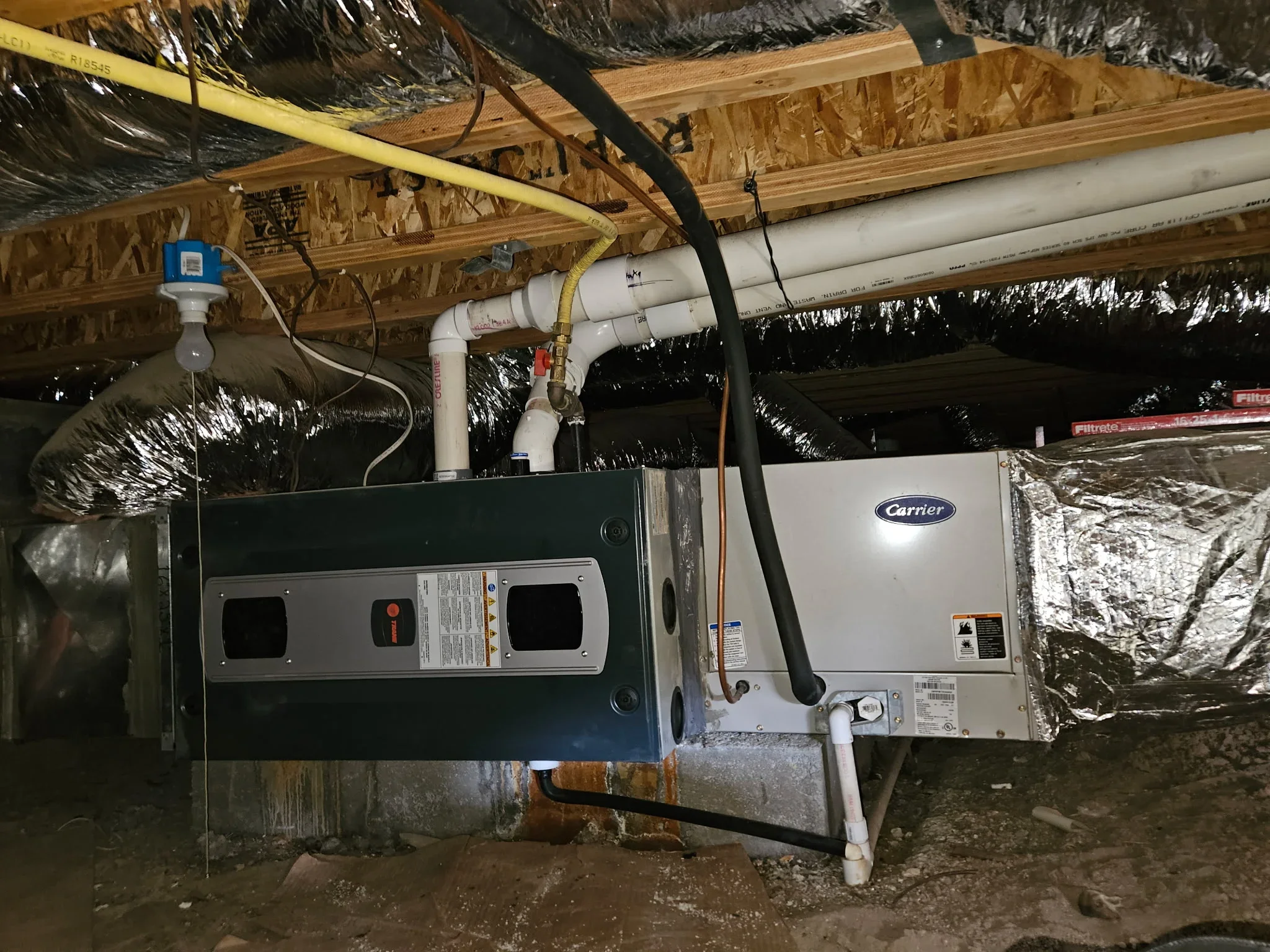 Carrier HVAC unit installed in basement with white ductwork and thermal insulation