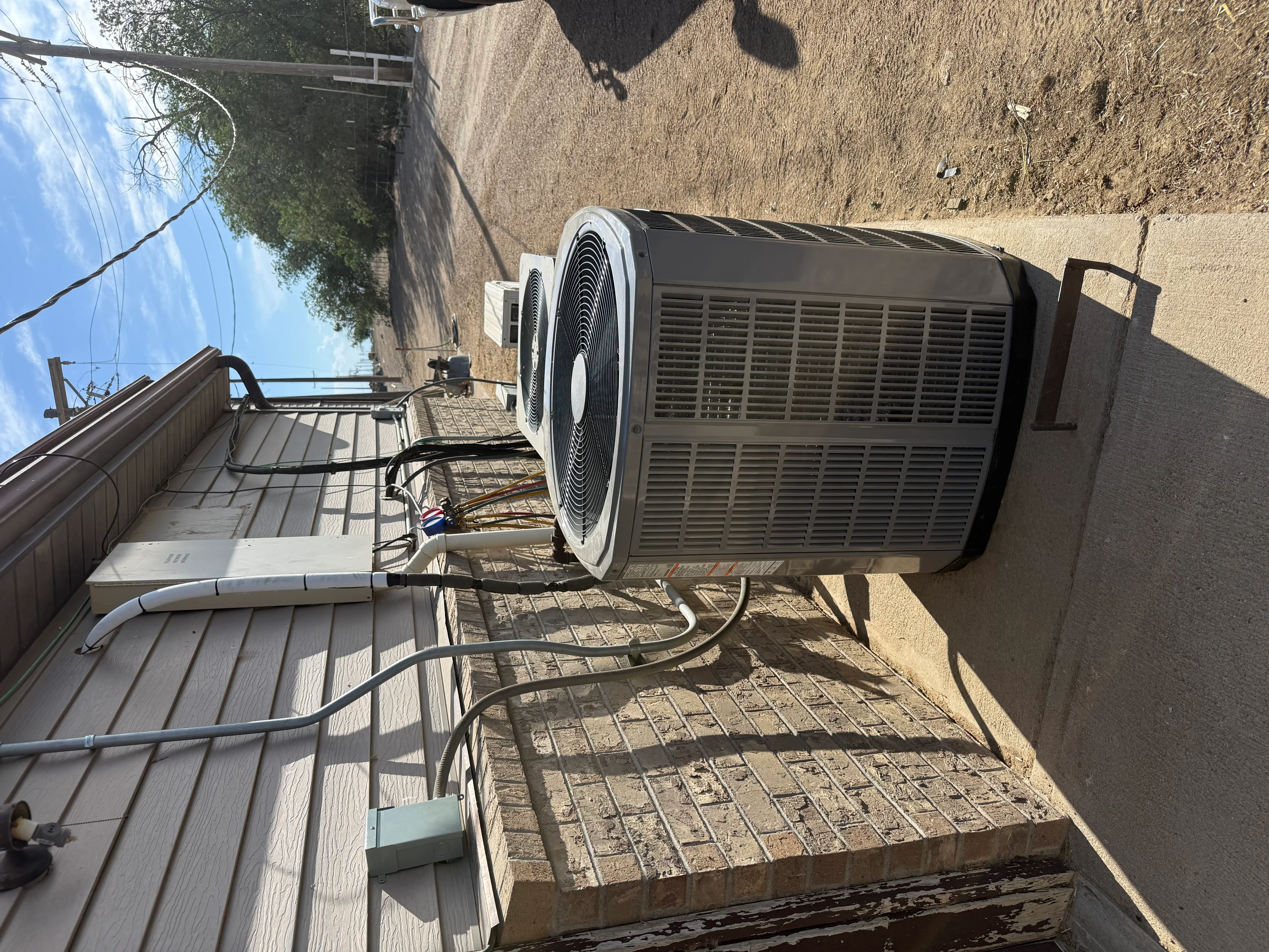 Outdoor AC condenser unit installed on concrete pad with electrical connections