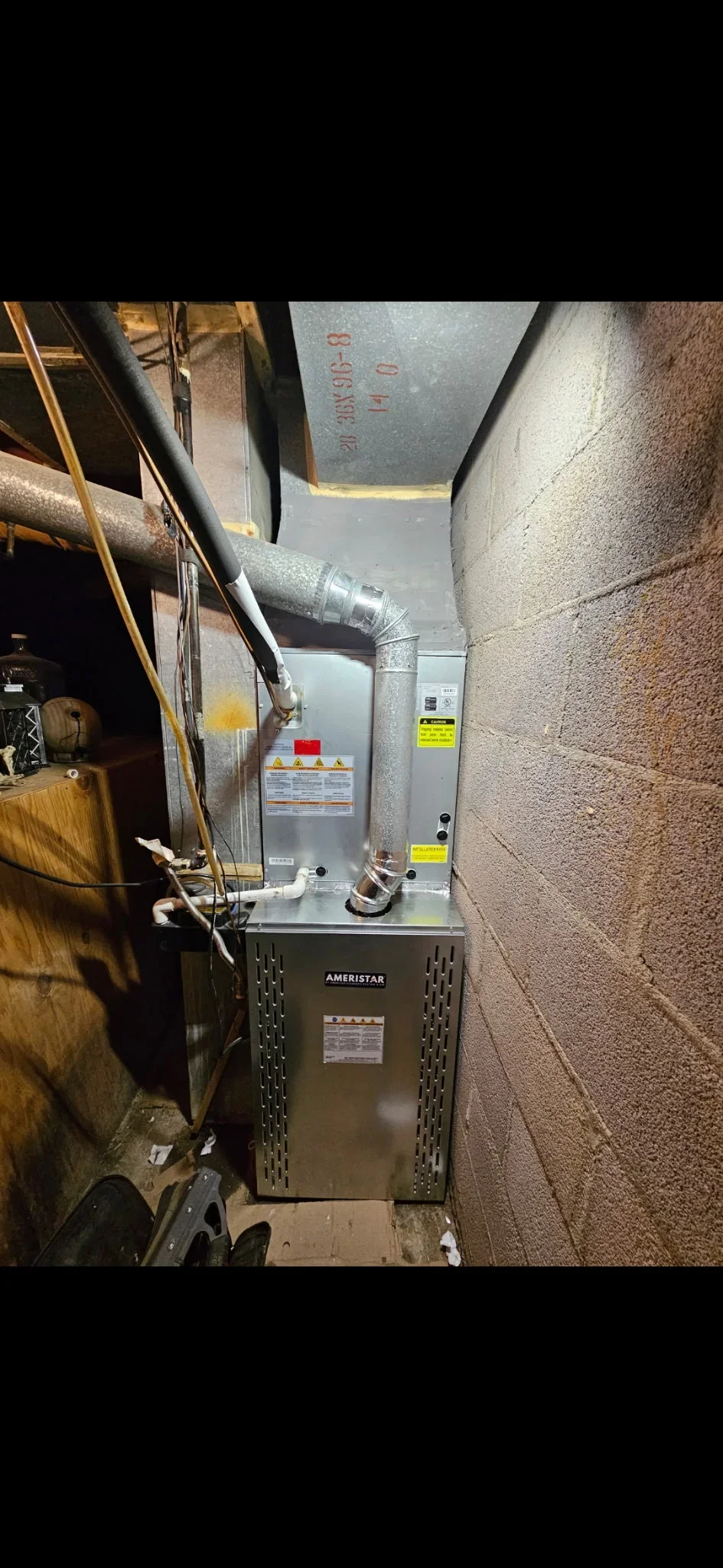 Newly installed Ameristar furnace in basement utility space with ductwork and safety labels