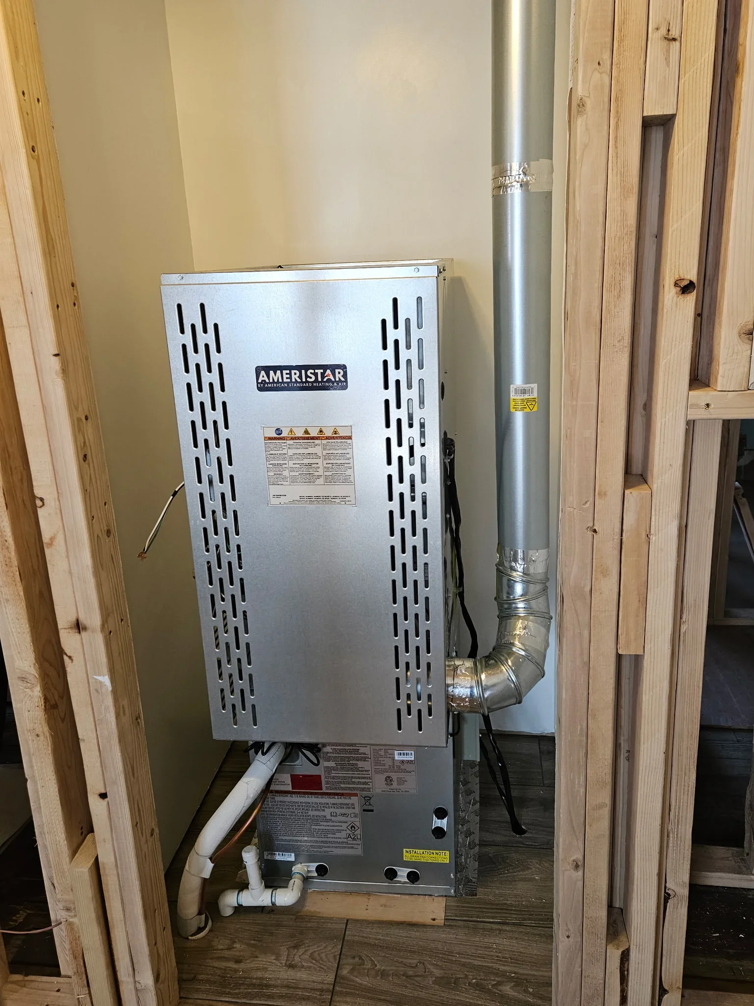 Ameristar tankless water heater with silver vent pipe installed in utility closet